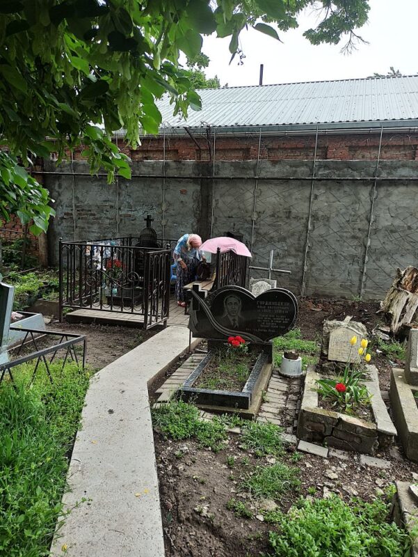 Женщина в прекрасном образе девочки-старушки стояла в оградке могилы отца Иоанна Попандопуло //Фото Инна Лебедева, Городской репортер